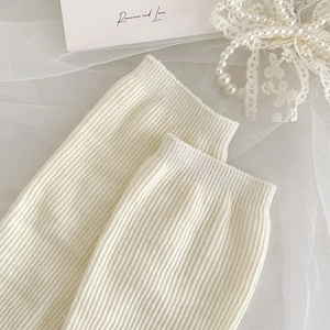 Detail of cream white vertical ribbed knit leg warmers with delicate lace trim