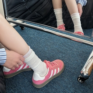 Dettaglio di sneaker in pelle scamosciata rosa con calze bianche a coste su tappeto