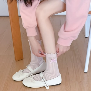 Detail of pink ruffled socks with plaid bows paired with white Mary Jane shoes