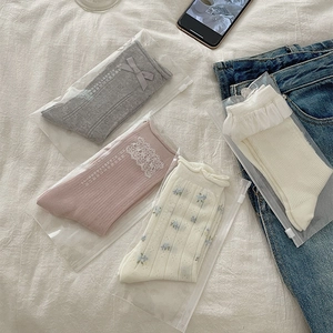 Detailed close-up of four-pack lace socks with grey bows and floral patterns in packaging