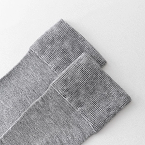 Nahaufnahme grauer Socken mit geripptem elastischem Bund und feiner Strickstruktur