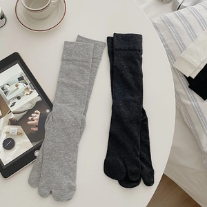 Detail of grey and black two-toe tabi socks with vertical ribbed texture on white table