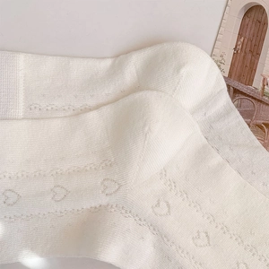 Close-up of white heart-shaped hollow knit socks with delicate ballet style texture