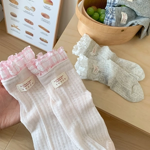 Detailed view of ballet style lace trim socks with pink plaid and cute woven labels