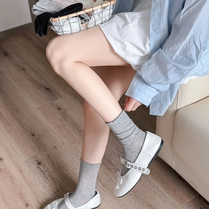 Détail de chaussettes grises à bordure dentelle avec des chaussures Mary Jane à nœud