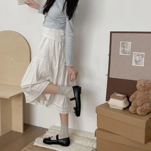 Detail of white tiered lace skirt paired with grey cotton socks and black Mary Jane shoes
