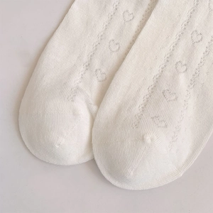 Close-up of white heart-shaped hollow-out knit pattern on breathable mid-calf socks