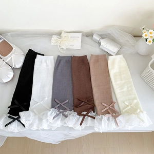 Close-up of ballet-style knit leg warmers with delicate lace trim and ribbon bows