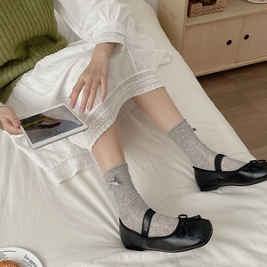 Close-up of grey ribbed crew socks with bow detail paired with black Mary Jane shoes