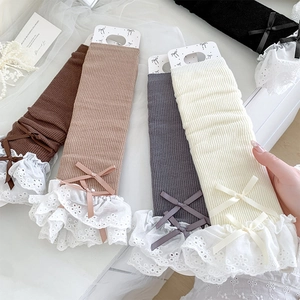 Close-up of knit leg warmers with lace trim and delicate bows in various neutral colors