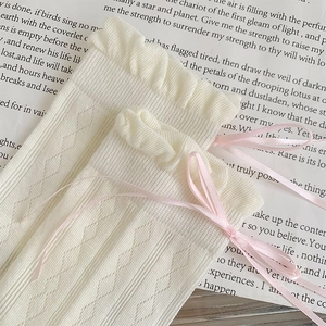Dettaglio calze in maglia crema con bordo in pizzo e fiocco di seta rosa elegante