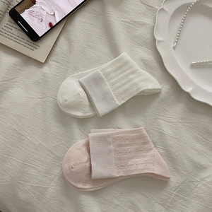 Close-up of white and pink ballet-style mesh socks with bow patterns on soft fabric