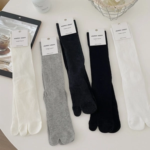 Detail of ribbed knit fabric on two-toe tabi socks in white, grey, and black