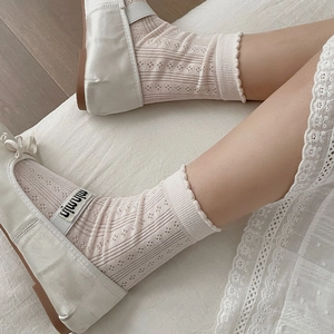 Close-up of pink hollow-out mesh socks with lace ruffles and ballet flat shoes