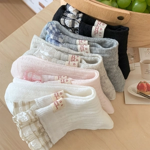 Detail of five pairs of ballet-style cotton socks with plaid ruffled edges and tags