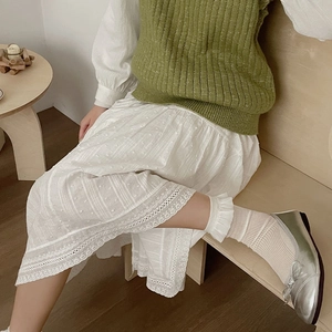 Detail of white lace socks with silver bow ballet flats and an embroidered skirt