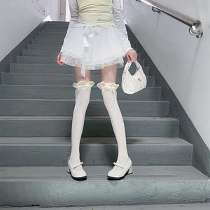 Detail of white over-the-knee socks featuring delicate lace trim and sweet ribbon bows