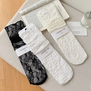 Close-up of white lace socks with floral patterns and bow details in elegant packaging
