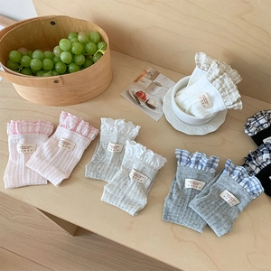 Detail of ballet style plaid socks with ruffled lace edges in various colors on a wooden table