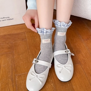 Close-up of ballet style grey knit socks with blue plaid ruffle trim and cloth labels