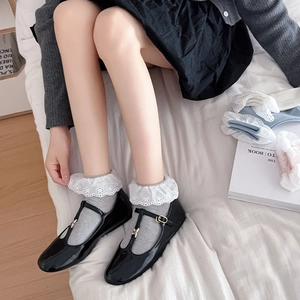 Detail of grey socks with white lace trim and black patent leather T-strap Mary Jane shoes
