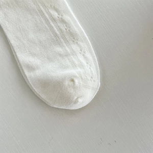 Dettaglio di calzini bianchi con pizzo e fiocchi caratterizzati da maglia traforata traspirante
