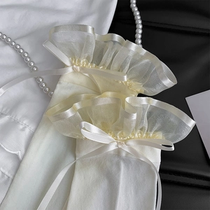 Detail of white thigh high socks featuring organza lace ruffles and satin ribbon bows