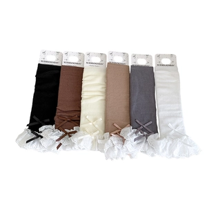 Six pairs of ribbed knit leg warmers with lace trim and bows in neutral colors