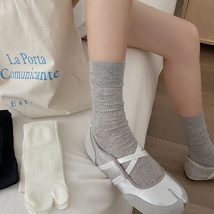 Grey vertical striped tabi socks worn with silver ballet flats in a cozy minimalist home setting