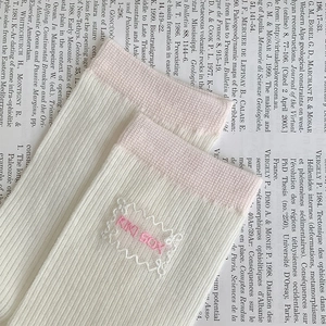 Detail of pink and white lace trim socks with KIKI BOX embroidery and ribbed cotton texture