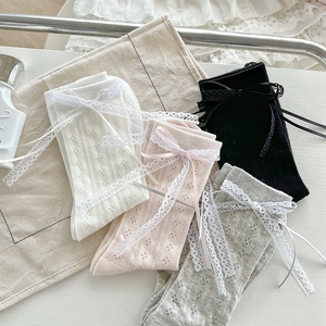 Dettaglio della trama a maglia di calze con fiocco in pizzo bianco rosa grigio nero