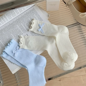 Detailed view of light blue and beige ruffle trim socks with cute bows and ribbed texture