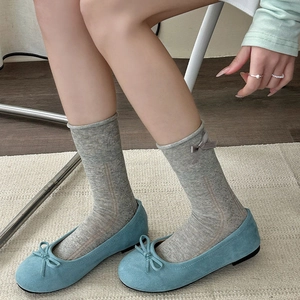 Detail of light blue suede ballet flats with gray ribbon bow socks on wooden floor