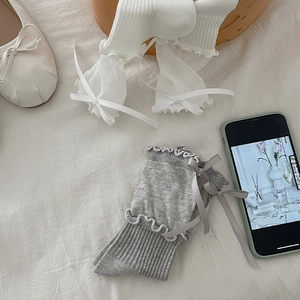 Detail of sweet ruffle trim socks with ribbon bows in white and grey colors