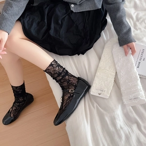 Close-up of ballet style lace socks with floral patterns and elastic cuffs in black and white