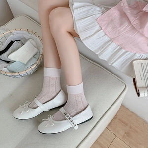 Close-up of pink heart-shaped cut-out mesh socks with white Mary Jane bow shoes
