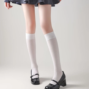 Detail von weißen Overknee-Socken mit elastischem Rippbündchen und schwarzen Mary Janes