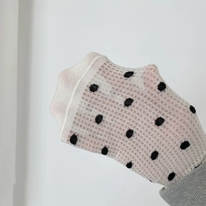 Detail showing white translucent mesh socks with black polka dots and elastic texture