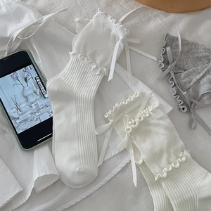 Detail of sweet ruffle trim and silk bow on ribbed cotton socks in soft white