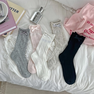 Close-up of five pairs of heart mesh socks with silk ribbons on a white bedsheet