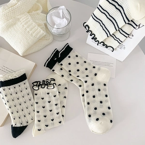 Detail of sweet heart pattern and ruffled cuffs on black and white cotton crew socks