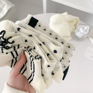 Detail showing breathable mesh knit texture and heart patterns on cream white mid-calf socks