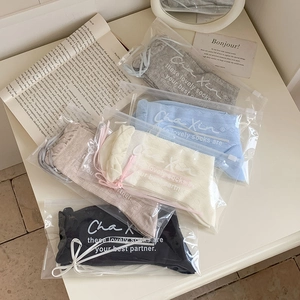 Dettaglio di calze in pizzo stile balletto con fiocco e maglia traforata in colori Morandi