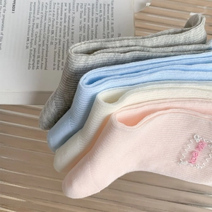 Detailed close-up of ribbed crew socks in pink and white with unisex embroidered label