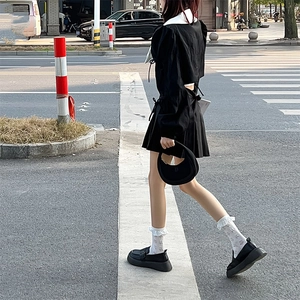 Détail de chaussettes jacquard Lolita à volants et mocassins avec une robe midi noire
