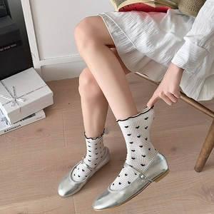 Detail of silver Mary Jane shoes with heart-patterned mesh socks and wavy cuffs