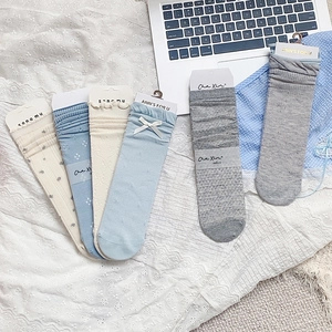 Detail of five pairs of blue and grey floral socks with bows on lace tablecloth