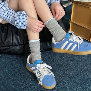 Dettaglio macro di sneakers in camoscio blu con strisce bianche e decorazioni di perle fini