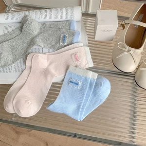 Detail view of pink and blue lace-edge socks with vertical texture and KIKI SOX embroidery