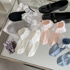 Detail of colorful cotton crew socks with wide white embroidered lace ruffles and rib knit